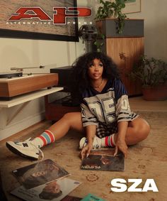 a woman sitting on the floor with her legs crossed in front of an album cover