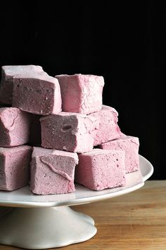 a white plate topped with pink marshmallows on top of a wooden table