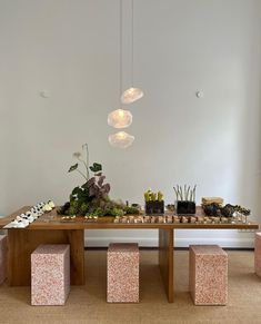 a wooden table topped with lots of food next to two vases filled with flowers