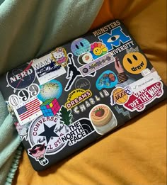 a laptop covered in stickers sitting on top of a bed