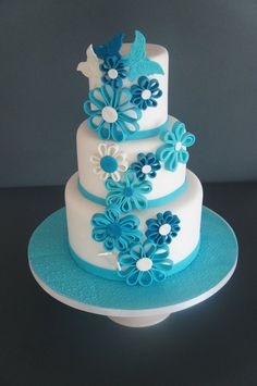 a three tiered cake with blue flowers on the top and white frosting in the middle