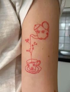 a woman with a tattoo on her arm has a cup and saucer in it