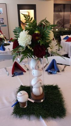 a vase filled with flowers and baseballs sitting on top of a white table cloth