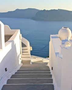 stairs leading up to the top of a building with water and mountains in the background