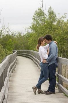 a man and woman embracing on a bridge