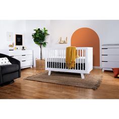 a baby's room with a white crib, black chair and brown rug