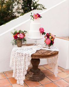 there is a table with flowers on it next to the stairs and a cake stand