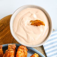 a blue plate topped with fried food next to a bowl of ranch dressing on top of a wooden table