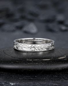 a wedding ring sitting on top of a black stone slab with rocks in the background