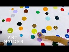 a man is painting on the wall with colorful circles