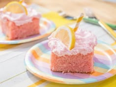 two pieces of pink cake on plates with lemon wedges