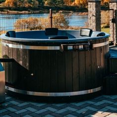 a hot tub sitting on top of a brick patio next to a body of water