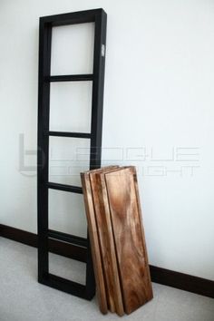 an empty room with a ladder leaning against the wall next to a wooden object on the floor