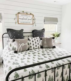 a bed with white and black pillows on it in a room that has wood paneled walls