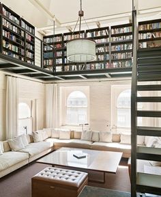 a living room filled with lots of books on top of a book shelf next to a loft bed