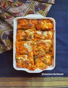 a casserole dish with cheese and vegetables in it on a blue table cloth