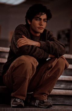 a young man sitting on top of a metal step next to stairs with his arms crossed