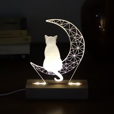 a white cat sitting on the moon shaped night light