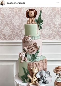 a three tiered cake with stuffed animals on it's top and the words jungle is one