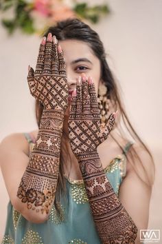 a woman holding her hands up to her face with henna designs on it's palms