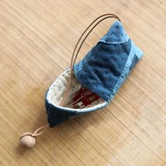 a miniature sailboat made out of fabric and string on a wooden table with a small ball