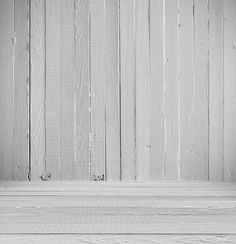 black and white photograph of an empty bench against a wooden wall with planks in the background