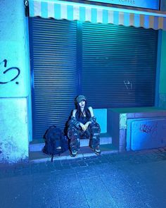 a person sitting on a bench in front of a building with graffiti written on it