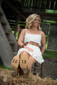 a woman sitting in a chair with her feet on the ground next to some hay