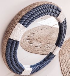 a round mirror sitting on top of a white floor next to rugs and baskets