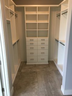 an empty walk in closet with white shelves and drawers on the wall, along with tile flooring