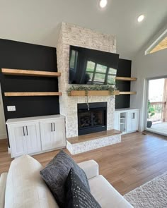 a living room with white furniture and a flat screen tv mounted on the wall above it