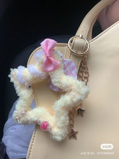 a white purse with a pink bow on it and a keychain attached to the handle