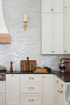 a kitchen with white cabinets and gold pulls on the knobs in the cabinet doors