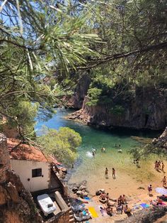 people are swimming and playing in the water at a beach near some rocks, trees and cliffs