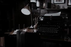 an old fashioned typewriter sitting on top of a wooden desk in a dark room