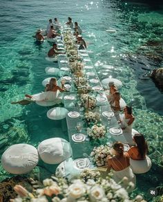 a long table is set up in the water for a wedding party with white flowers on it