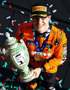 a man in an orange jacket is holding a green fire hydrant and confetti