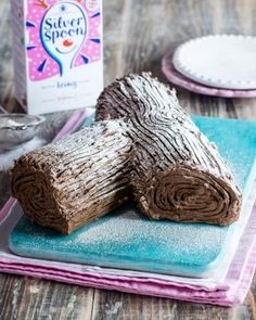 two pieces of cake sitting on top of a blue and pink napkin next to a box of sugar