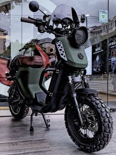 a motorcycle parked in front of a store window with the reflection of another bike behind it