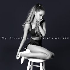 a black and white photo of a woman sitting on a stool