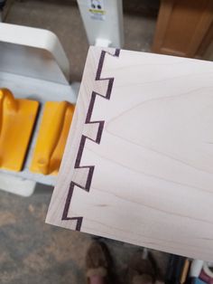 a person holding up a piece of wood with the word cut out on it and yellow chairs in the background