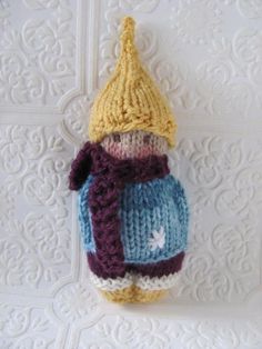 a crocheted hat and sweater hanging from a hook on a white wallpaper