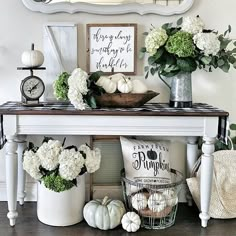 a table with white flowers, pumpkins and other decorations on it in front of a mirror