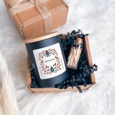 an open box with two candles inside on a white furnishing next to a brown gift box