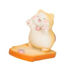 a small white cat figurine sitting on top of an orange base with its paws in the air