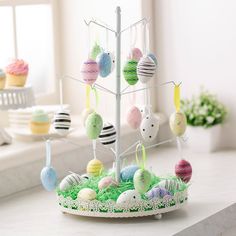 an easter tree is decorated with cupcakes and other colorful decorations on the table