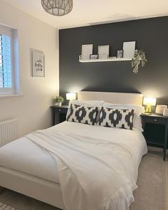 a white bed sitting in a bedroom next to two lamps on either side of the bed