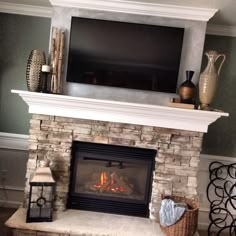 a fireplace with a flat screen tv above it and candles on the mantle next to it