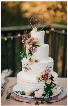 a white wedding cake with pink flowers and greenery