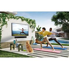 two people doing yoga in front of a flat screen tv with a dog looking on